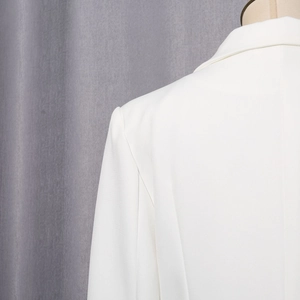 Vue détaillée des coutures d'épaule et du col ajusté de ce blazer blanc élégant