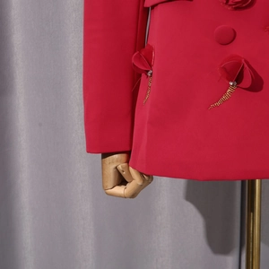 Detail eines roten Blazers mit 3D-Blütenblättern, Strasssteinen und goldenen Quastenketten