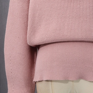 Close-up of pink knit sweater showing ribbed hem and sleeve seam construction details