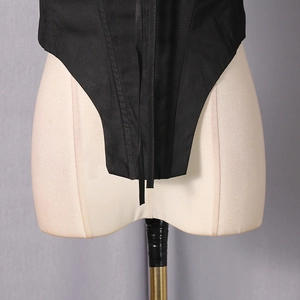 Detail view of the black corset vest showing the boning structure and pointed hem design