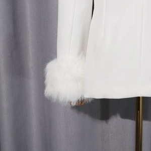 Détail du blazer blanc avec des poignets élégants en fausse fourrure sur la manche