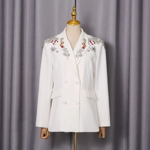 Detailaufnahme der handgefertigten Pailletten- und Perlenstickerei auf einem weißen Blazer