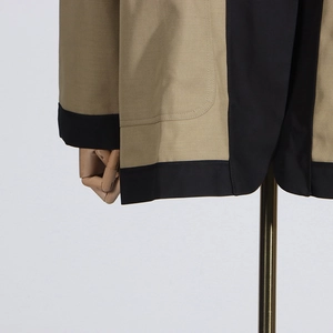 Detail view of khaki and black contrast color blazer with large patch pockets