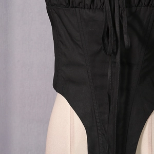 Detail view of black corset top with boning structure and front lace-up fastening