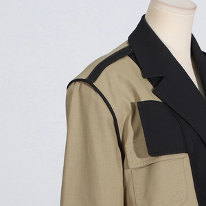 Detailed close-up of khaki blazer with black contrast stitching and lapel pocket