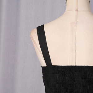 Detail view of black smocked fabric texture and wide shoulder straps on a casual top