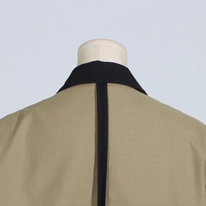 Close-up of khaki blazer back with black contrast collar and central decorative tape detail