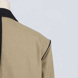 Detail of khaki blazer with black contrast collar and piped seams on a mannequin