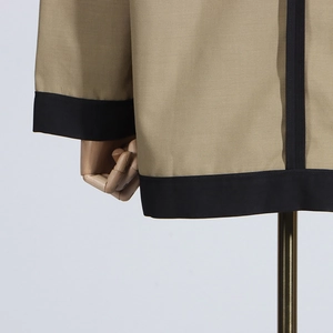 Detailed view of khaki blazer featuring contrast black trim on cuffs and hemline edge