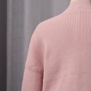 Close-up of pink knit sweater featuring vertical ribbed texture and refined neckline detail