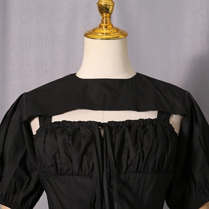 Detail of black top featuring puff sleeves, pleated chest, and hollow-out lace-up design