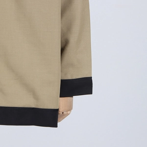 Detailed close-up of khaki blazer with black contrast trim on premium twill fabric