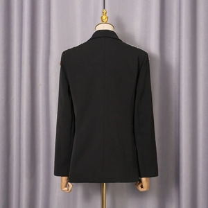 Detailansicht der Rückseite eines schwarzen Blazers mit Schulterpolstern und bunter Stickerei