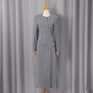 Detail of the unique diagonal button closure on a dark grey wool blend maxi coat