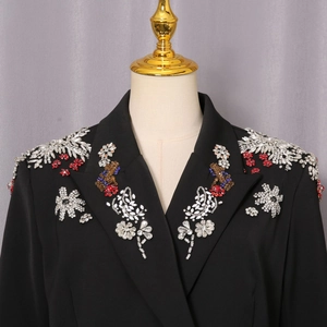 Detail der schweren Handperlenstickerei und Kristalle auf der schwarzen Blazer-Schulter