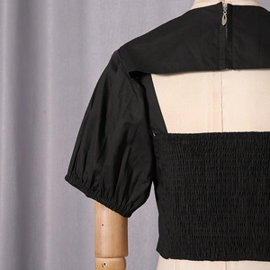 Detail of black top featuring smocked back panel, puffed sleeves and cut-out design