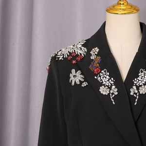 Detail eines schwarzen Blazers mit aufwendiger Stickerei aus bunten Strasssteinen