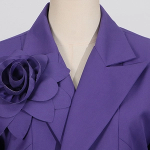 Detail of deep purple blazer featuring a large 3D fabric flower on the notched lapel