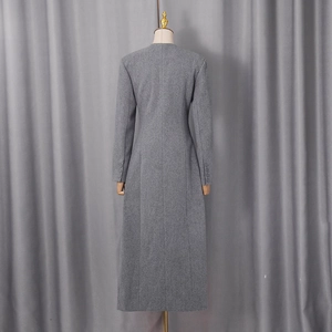 Detail view of the back of a grey long wool coat with slim waist and buttoned cuffs