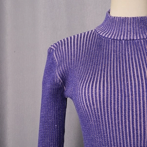 Dettaglio del collo alto e della trama a costine sul maglione a righe viola aderente