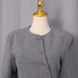 Detailed macro of a grey wool coat featuring asymmetric button closure and thick texture