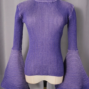 Dettaglio del maglione viola in maglia a coste con maniche a campana e righe fini