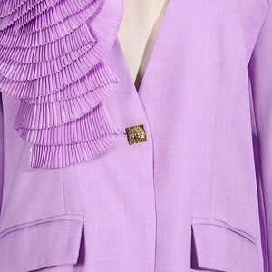 Detail of purple blazer featuring asymmetric organza ruffles and a gold vintage button