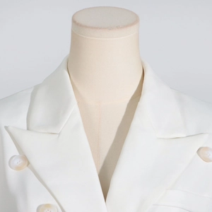 Close-up of white double-breasted blazer with notch lapel and marble texture buttons