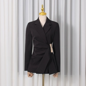 Detailed close-up of a black slim-fit blazer featuring asymmetric waist pleats and metal buckle