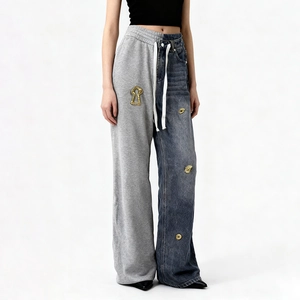 Detail of grey sweatpants and blue denim patchwork design with gold metal accents