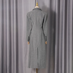 Rear view detail of a long grey wool coat featuring a back slit and decorative buttons