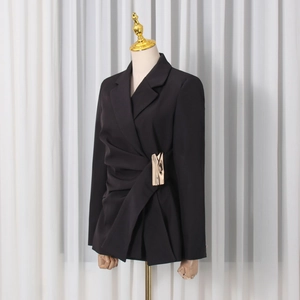 Detailed view of black tailored blazer with unique gold metal buckle and pleated waist