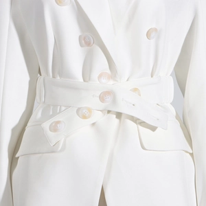 Detail of white double-breasted blazer with matching belt and glossy cream buttons