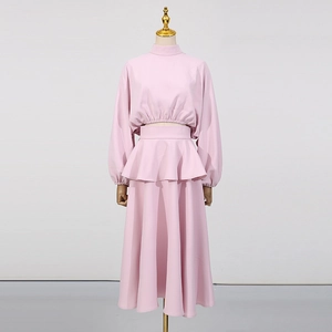 Détail d'un ensemble rose deux pièces avec col montant, taille volantée et manches bouffantes