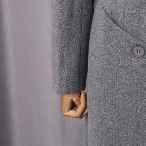 Detailed close-up of grey wool coat cuff with matte button and premium fabric texture