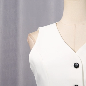 Close-up of minimalist white V-neck vest featuring sharp tailoring and black contrast buttons