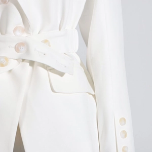 Detail of white blazer showing beige buttons, waist belt pleats and side pocket flap
