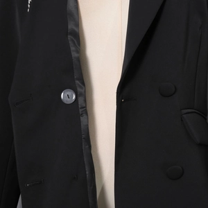 Detailansicht eines schwarzen Blazers mit zweireihigen Knöpfen und Satinkragennaht