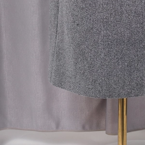 Detailed close-up of grey wool blend fabric texture and professional sewing on coat hem