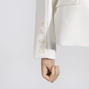 Close-up of four marble-patterned buttons on the sleeve of a white tailored blazer