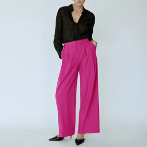 Detail der hoch taillierten rosaroten weiten Hose mit eleganten Falten und Fallstoff