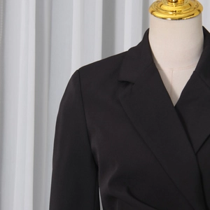Detailed close-up of notched lapels and shoulder tailoring on a black blazer jacket