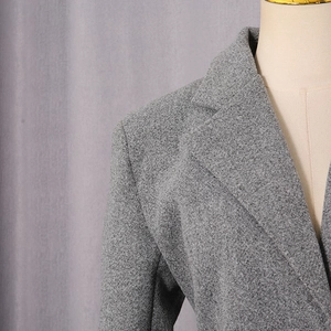 Detail of grey wool coat showing notch lapels and textured tweed fabric on a mannequin