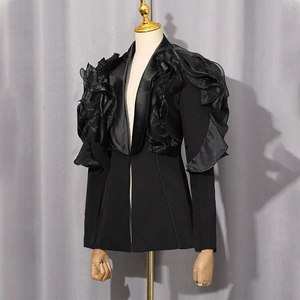 Detail view of bold ruffled organza sleeves on a tailored black women's blazer