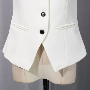 Detail of white tailored vest showing contrast black buttons and welt pockets