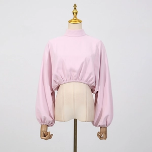 Détail du haut court rose à col montant et manches lanternes sur un mannequin de couture