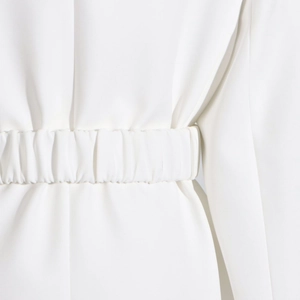 Detailed close-up of white gathered elastic waist design on minimalist tailored blazer