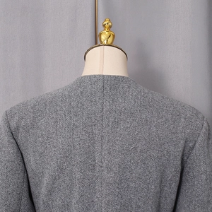 Detail view of the gray woolen coat back, featuring textured fabric and round neckline