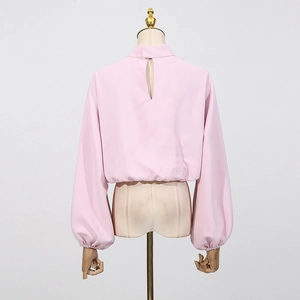 Détail du haut rose à manches lanternes et dos découpé en goutte sur un mannequin