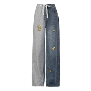 Detail of asymmetric wide-leg pants with blue denim, grey fabric and gold charms